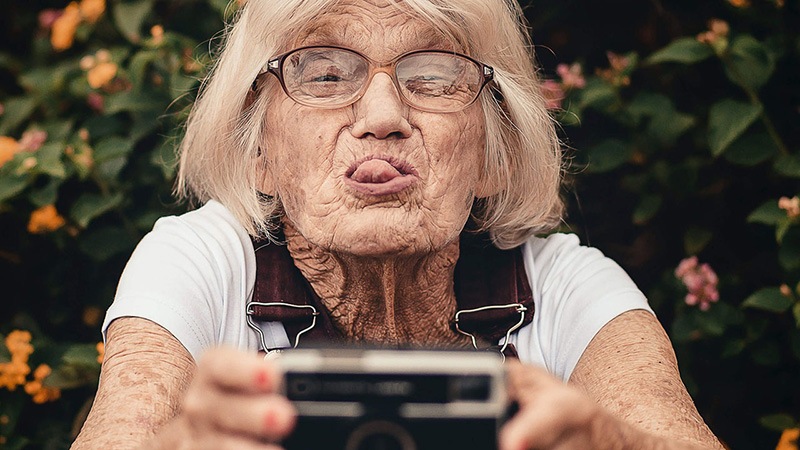 eine glückliche ältere Frau mit einem Polaroid Fotoapparat