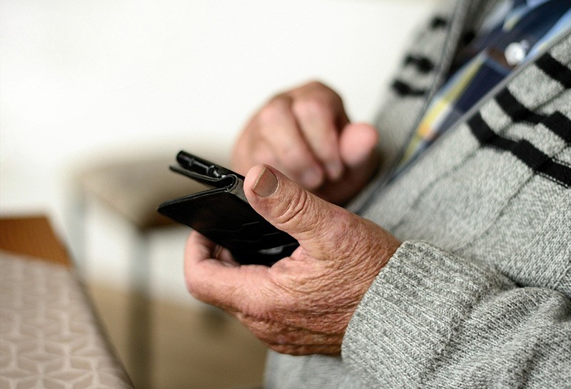 Ein ältere Mann bedient ein Handy zum Online einkaufen